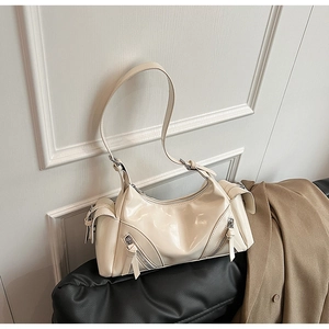 Close-up of beige dumpling bag with zipper pockets and tassel details in biker style