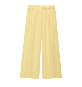 Détail d'un pantalon large en lin jaune clair montrant les plis et passants de ceinture