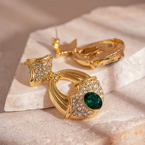 Macro de boucles d'oreilles dorées vintage avec pierres vert émeraude et cristaux brillants