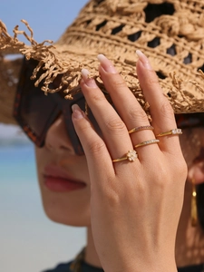 Close-up of stacked gold adjustable rings with 5A zircons and floral motifs on a model