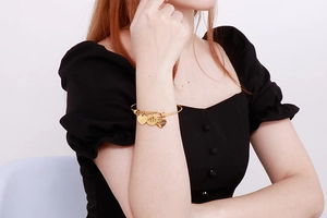 Detail of gold family charm bracelet featuring a heart and silhouettes on a woman's wrist