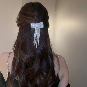 Vue détaillée de la pince à cheveux noeud argenté avec de longs pompons en strass brillants