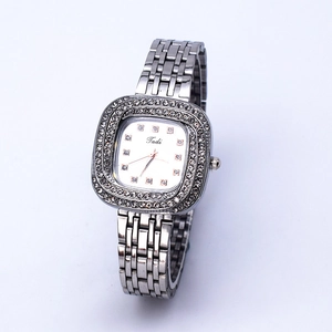 Macro shot of silver square dial with rhinestone bezel and polished metal link strap