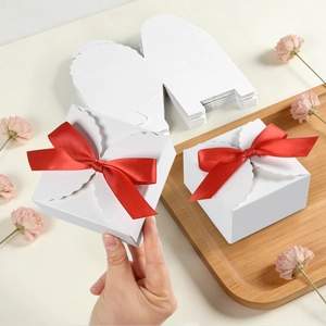 Detailed view of white paper gift box with red silk bow and elegant scalloped edge design