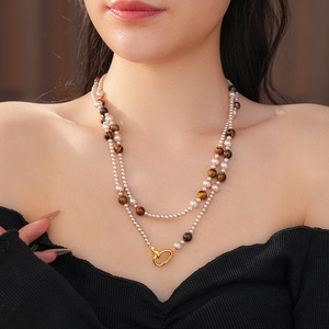 Détail d'un collier double couche avec perles blanches, pierres œil de tigre et fermoir doré