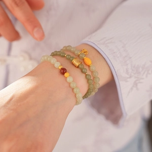 Detail of elegant stacked Hetian jade bracelets on wrist with traditional Chinese outfit