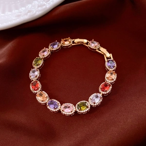 Macro shot of vintage gold bracelet featuring colorful oval zircons on red silk fabric