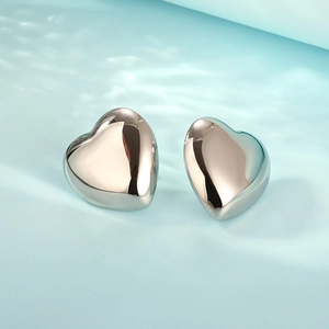 Polished silver 18K gold stainless steel hollow heart earrings on light blue background