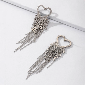 Close-up of silver heart earrings featuring sparkling rhinestones and long tassel drops