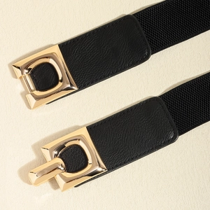 Detail view of gold geometric metal buckle and black textured leather belt material