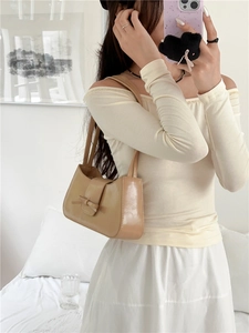 Detail of khaki PU leather baguette bag with bow decoration worn on the shoulder