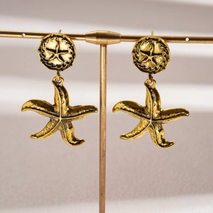 Macro view of vintage gold starfish earrings with textured geometric design on T-stand