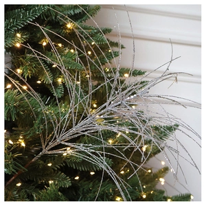Close-up of sparkling silver glitter branches for Christmas tree decor with festive lights