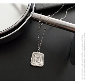 Macro detail of butterfly shell pendant on a refined silver beaded necklace chain