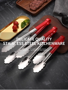 Three sizes of stainless steel food tongs with red handles on dark marble kitchen counter