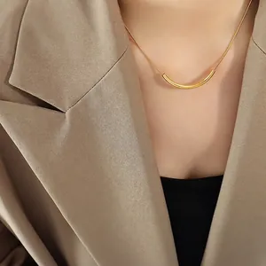 Collier sourire minimaliste doré avec pendentif incurvé porté sur un modèle élégant