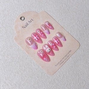 Close-up of pink almond press-on nails with 3D bunny, floral charms, and bow art