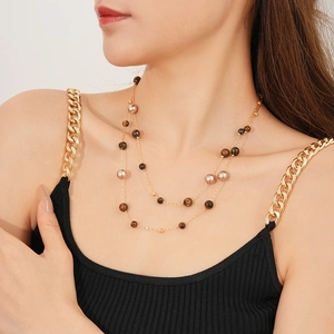 Close-up of double-layer gold tiger eye and pearl long necklace on a model detail