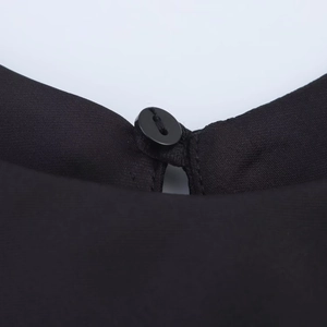 Dettaglio del retro del collo di un abito midi in raso nero con chiusura a bottone