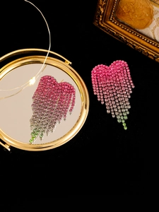 Macro detail of rhinestone heart tassel earrings with colorful gradient crystal fringe