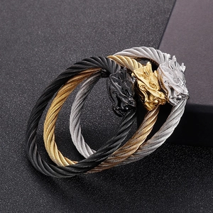Détails de trois bracelets punk à tête de dragon en finitions or, argent et noir mat