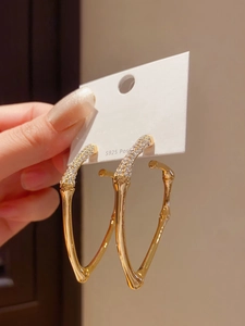 Close-up of S925 silver needle gold bamboo earrings with sparkling rhinestone pavé