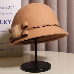 Detail view of camel wool cloche hat featuring a plush fur ball and elegant bow ribbon