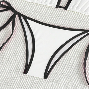 Detail of high-cut bikini bottoms in white with black trim and side tie closure