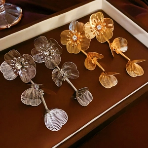 Vue détaillée de boucles d'oreilles fleuries dorées et argentées avec strass brillants