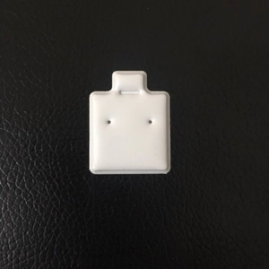 White square earring display card with two holes on a black leather background texture