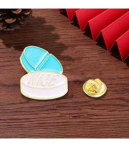 Detailed shot of a blue and white pill enamel pin with gold NICE text on a wooden desk