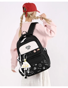 Rear view of primary school girl wearing a black and white bear backpack with plush charm