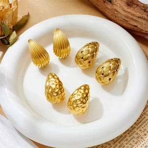Detailed view of three pairs of gold teardrop earrings with textured finishes in a tray