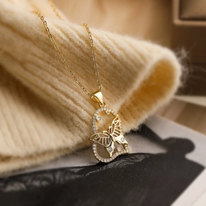 18K gold plated necklace featuring a zircon heart and butterfly pendant on a beige knit sweater