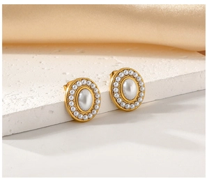 Detail of gold-plated stud earrings featuring a large oval pearl framed by small pearls