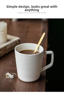 Detailed view of white embossed ceramic mug with vertical stripes and golden mixing spoon