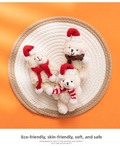 Close-up of three plush Christmas bears with festive scarves and red hats on a woven mat