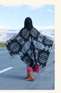 Rear view of ethnic hooded poncho with geometric patterns and tassels in a desert landscape