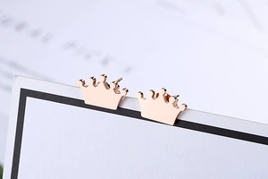Macro shot of rose gold crown stud earrings on a white card with a minimalist design