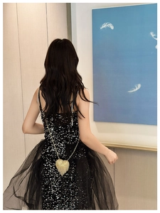 Detail of a mini heart-shaped rhinestone handbag paired with a black sequin tulle dress