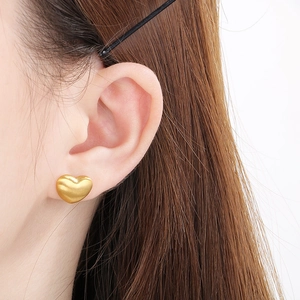 Boucles d'oreilles cœur dorées minimalistes avec finition mate brossée sur modèle