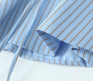 Detailed view of light blue striped fabric with brown stripes and fine double stitching