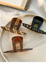 Close-up of three acetate hair claws in tortoise shell, black, and marble blue finishes
