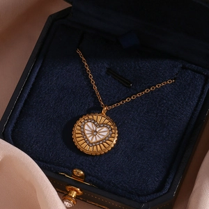 Gros plan détaillé du pendentif médaille doré avec cœur blanc et cristaux brillants
