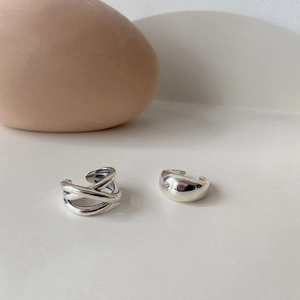 Detailed view of silver minimalist crisscross ring and smooth thick band on stone base