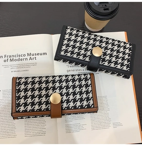 Chic houndstooth long wallets with leather trim and gold snap button on magazine background
