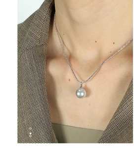 Close-up of a large grey pearl pendant on a textured silver chain worn with a blazer
