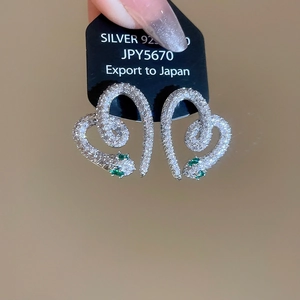 Detailed view of S925 snake earrings with white zircons and green gemstone eyes