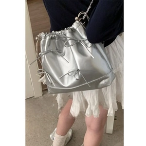 Detail of silver bucket bag featuring cute bow knots and stylish metal chain strap