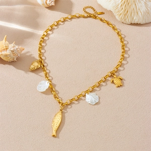 Gold ocean-themed necklace with fish and shell charms on a sandy beach background